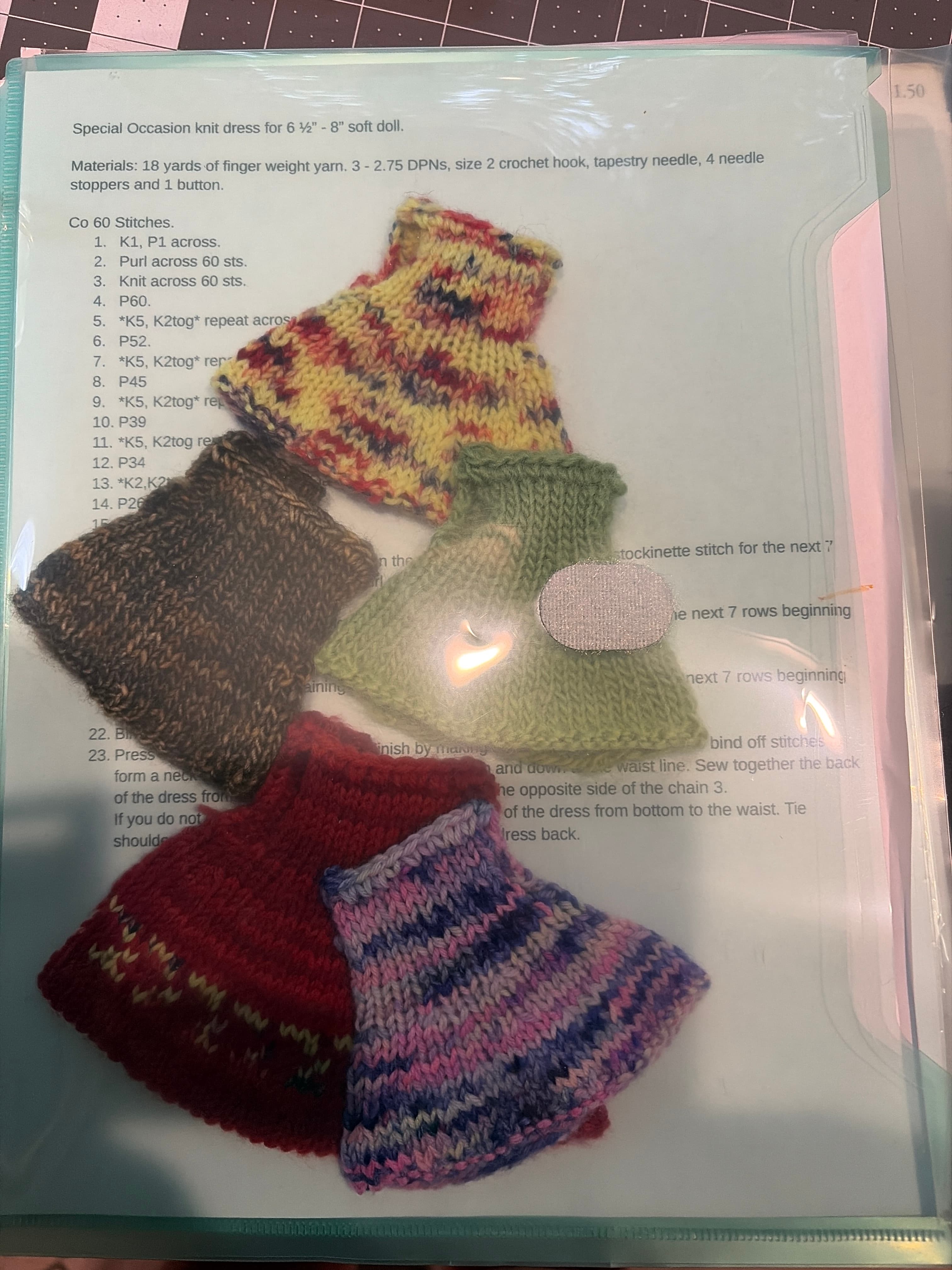 Knit doll dresses in berry, green and brown variegated yarn on the special occasion dress pattern.